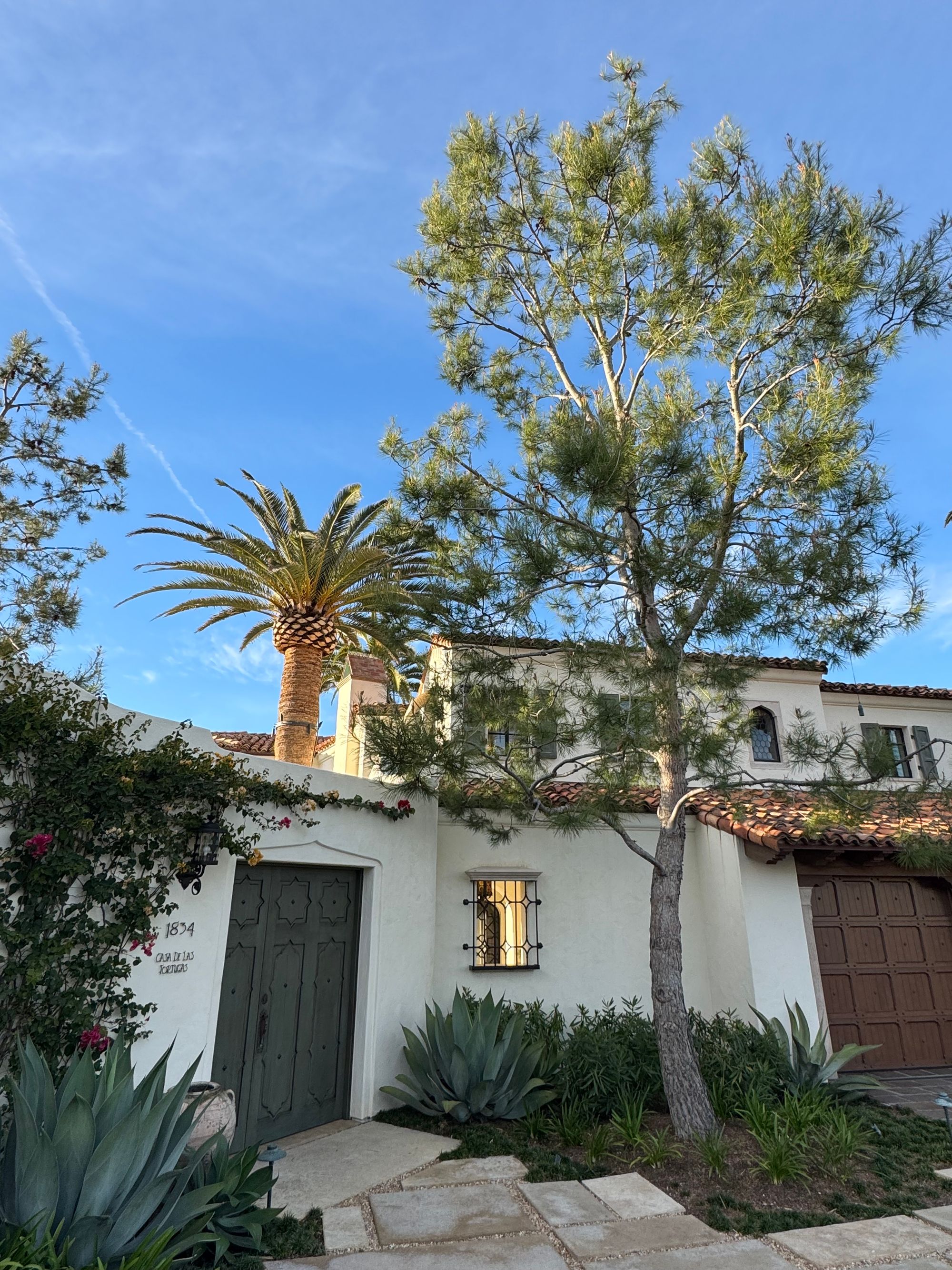 A Spanish revival home with palm trees on a sunny day