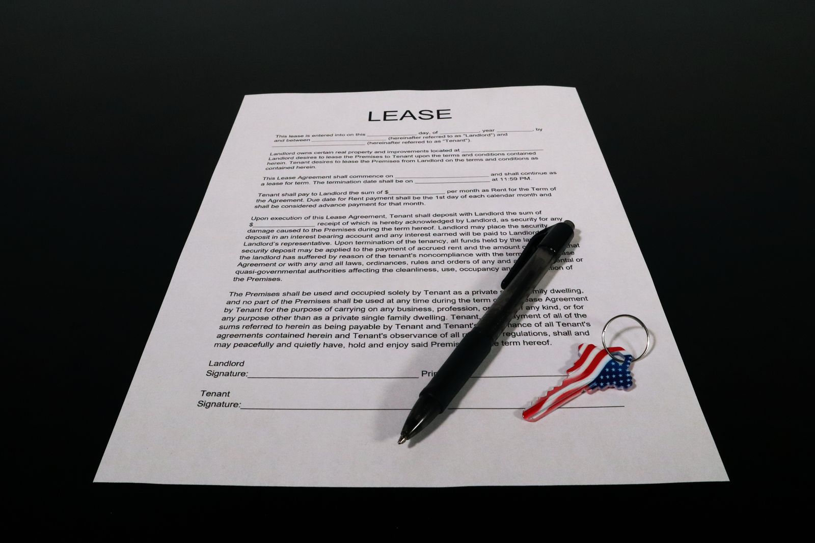 Printed residential lease agreement on a dark table with a pen and a keyring resting on the signature page