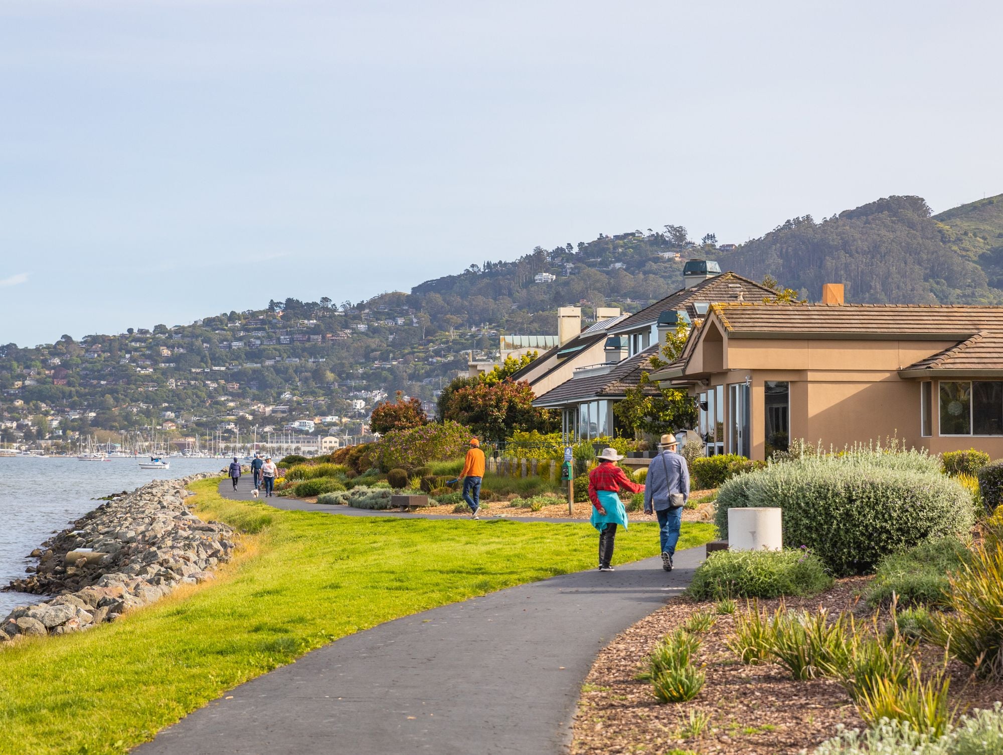 People walking along a scenic path in a coastal residential area