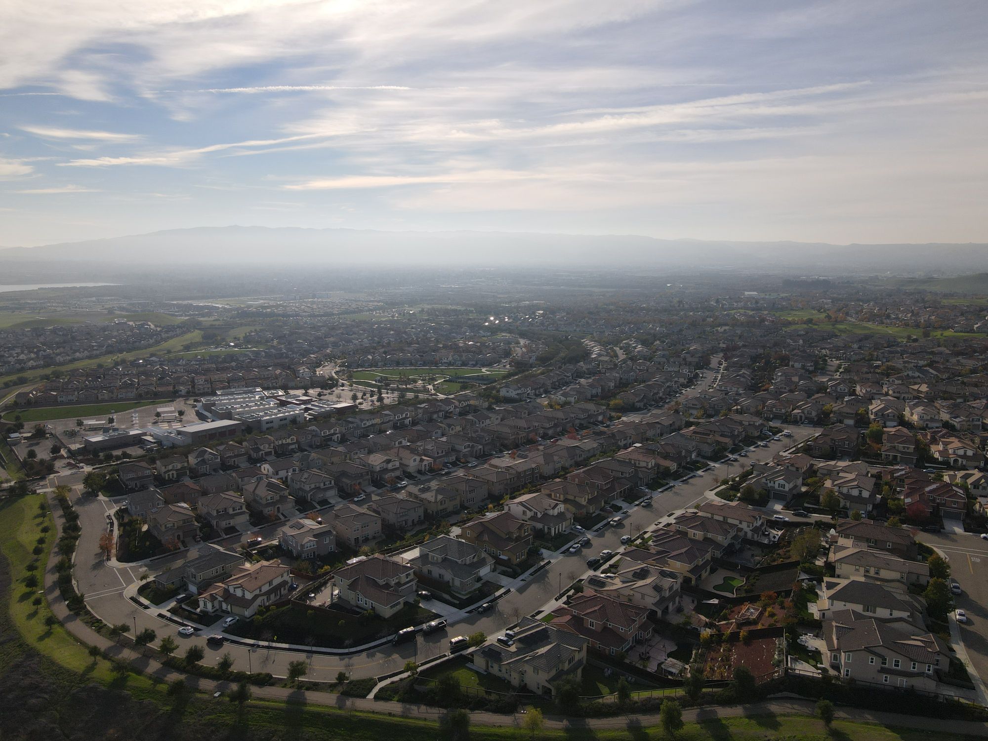 Aerial view of a residential area with clear skies and hills in the distance
