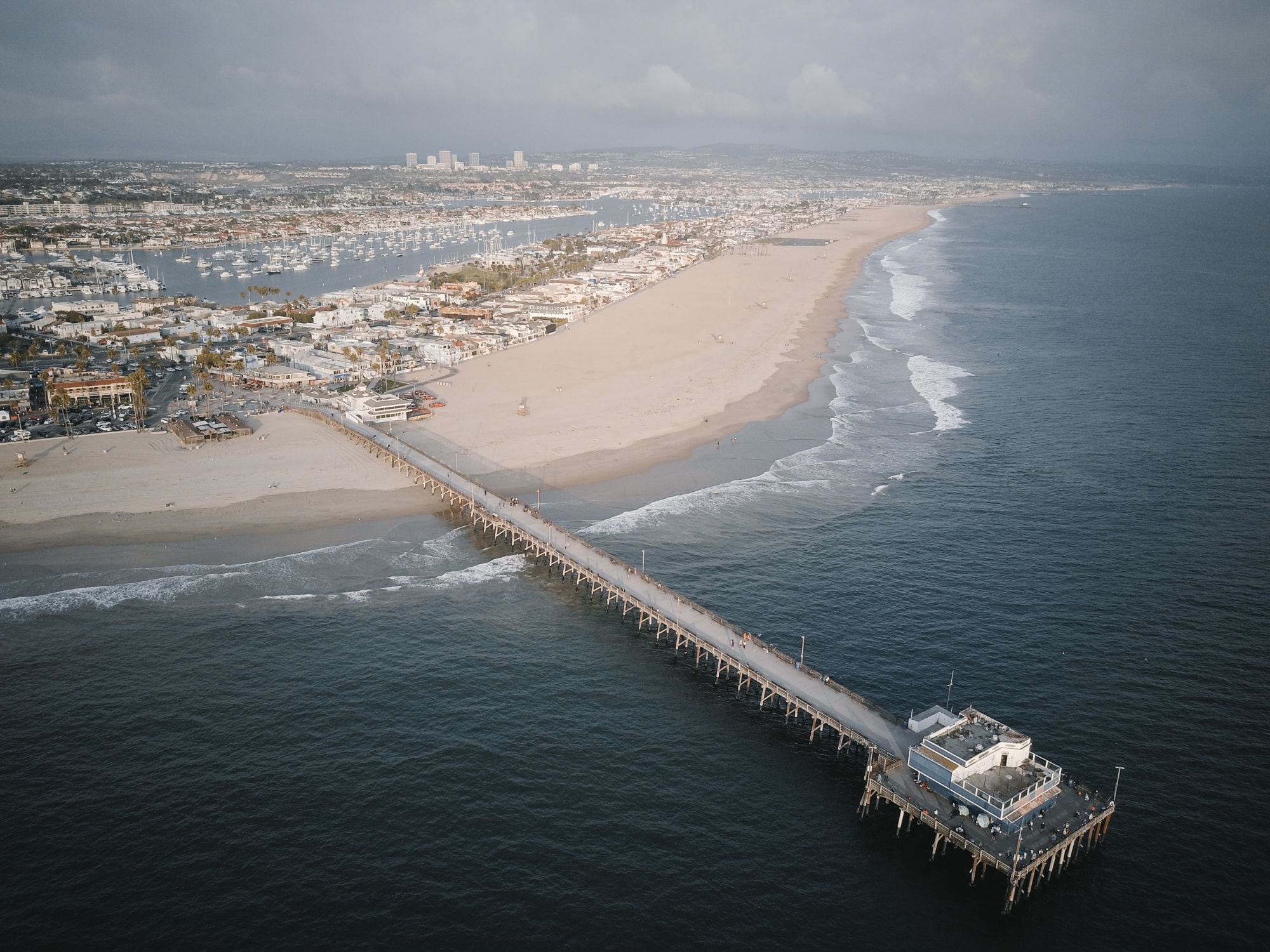 Aerial view of a pier reaching into the ocean beside a coastline