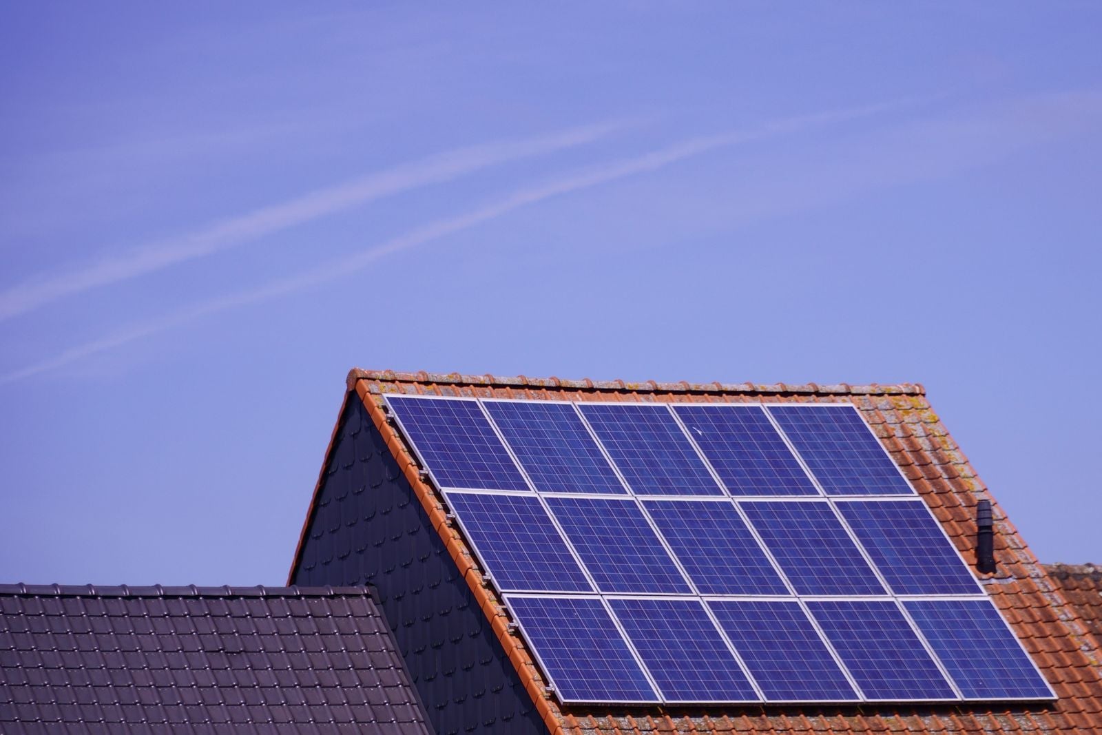 Close-up of solar panels mounted on a tile roof under a clear sky