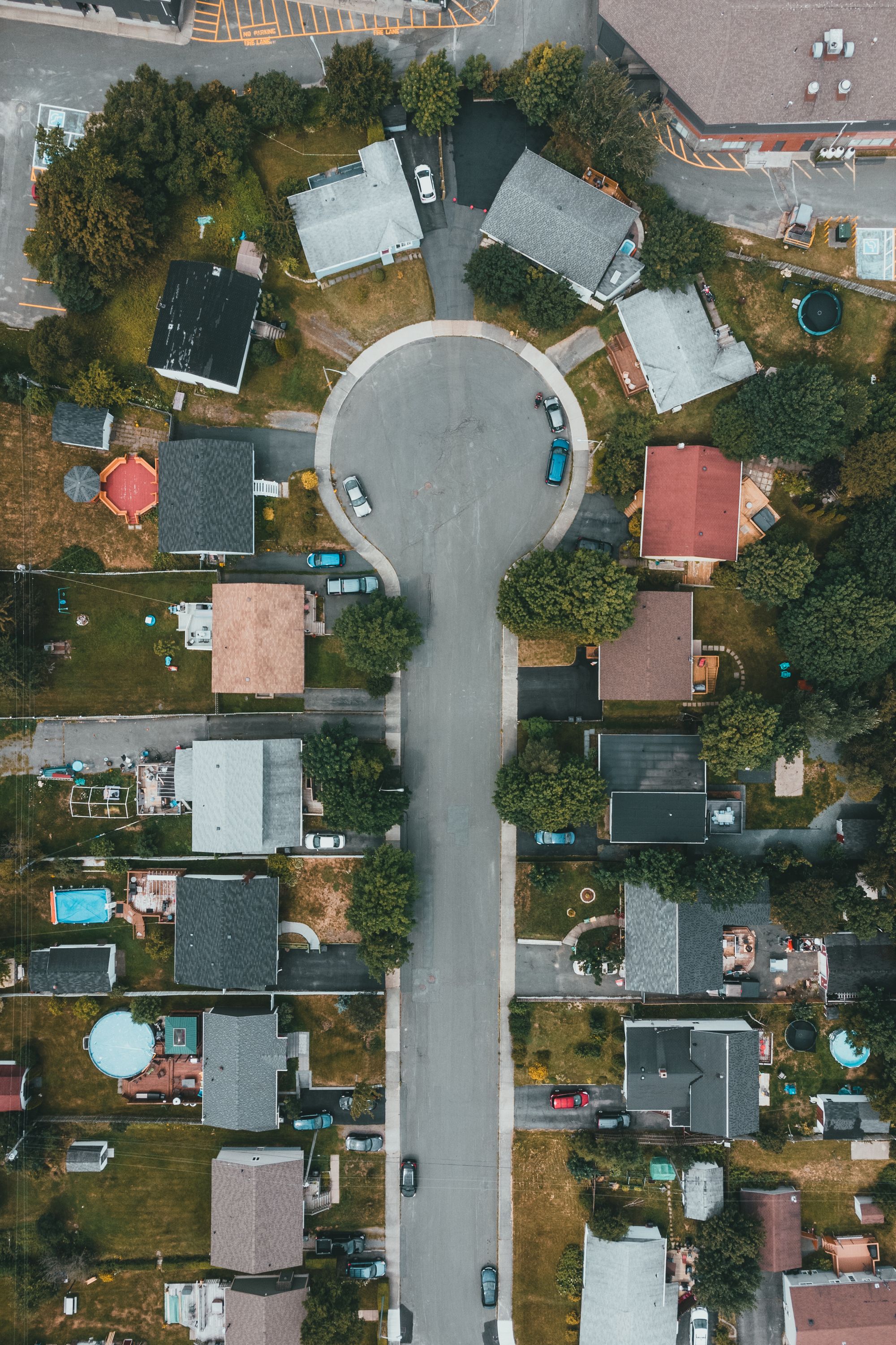 High angle aerial view of a suburban cul de sac surrounded by houses and trees