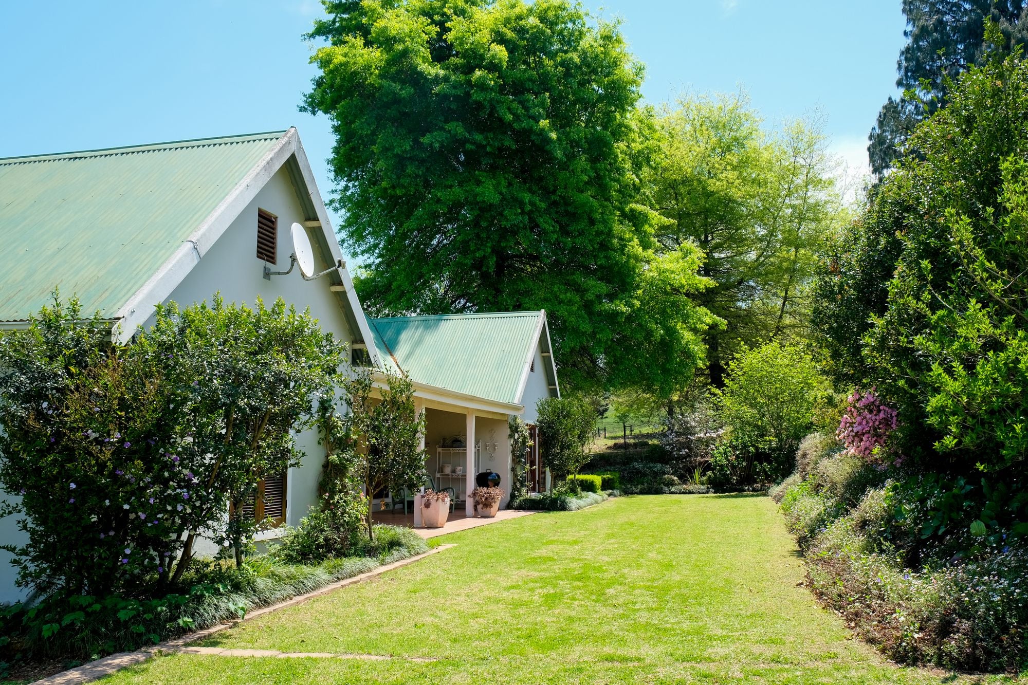 A cottage with a green garden under a vibrant blue sky