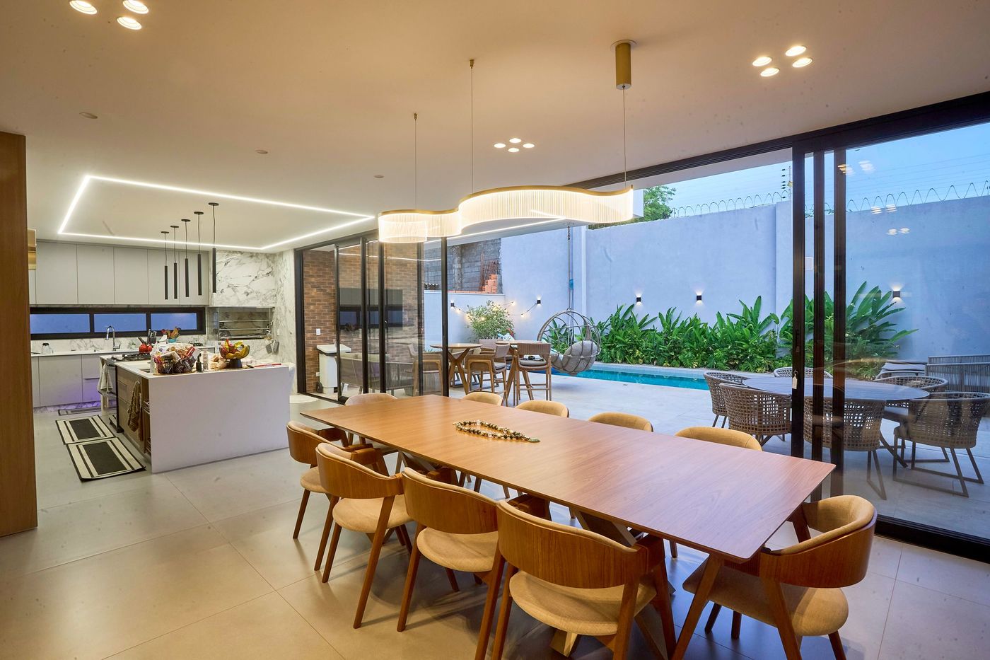 Modern dining room with sliding glass walls opening to a pool terrace