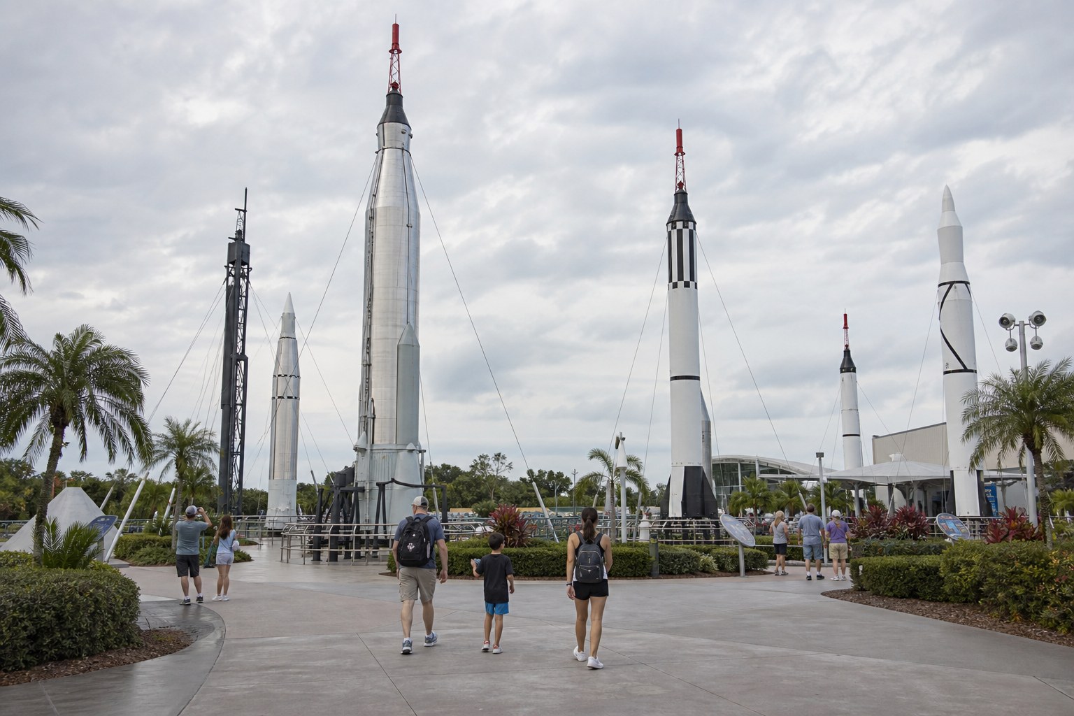 Illustration of visitors walking among realistically scaled rockets at Kennedy Space Center's Rocket Garden