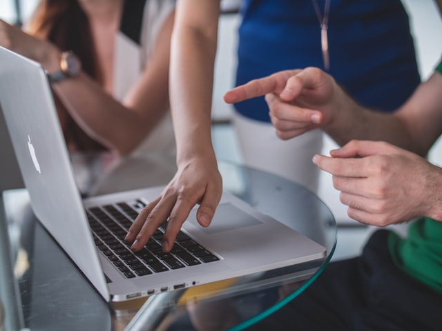 a group of people sitting around a computer in an office