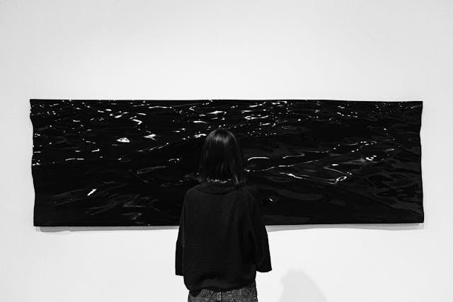 a person looking at a black piece of art on the wall