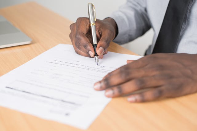 A person using a silver pen to sign a document