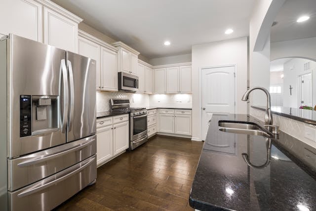 a white kitchen with modern appliances and dark counters