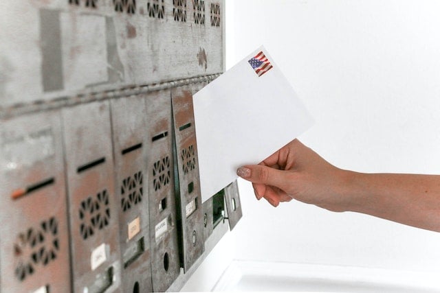 person placing a letter into a community mailbox