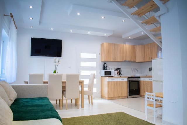 an open concept living room and kitchen with white walls and light wood cabinets