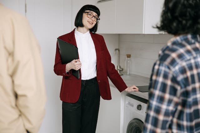 a landlord in a red jacket smiling while talking with two tenants