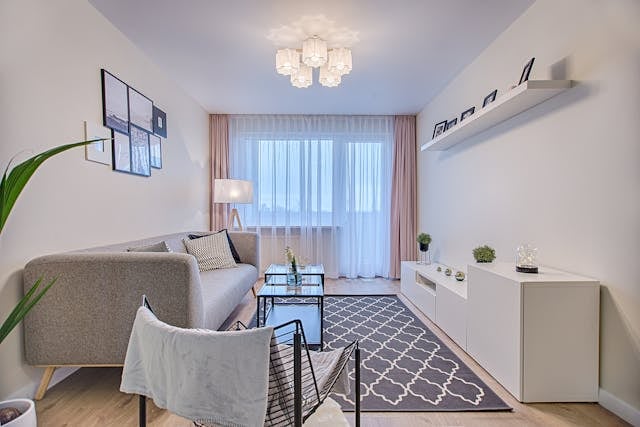 a white living room with grey furniture and a large window