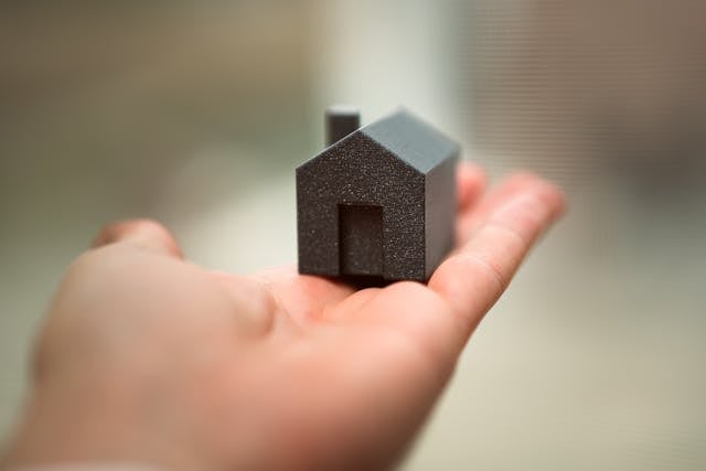 a small black home figurine in the palm of a hand