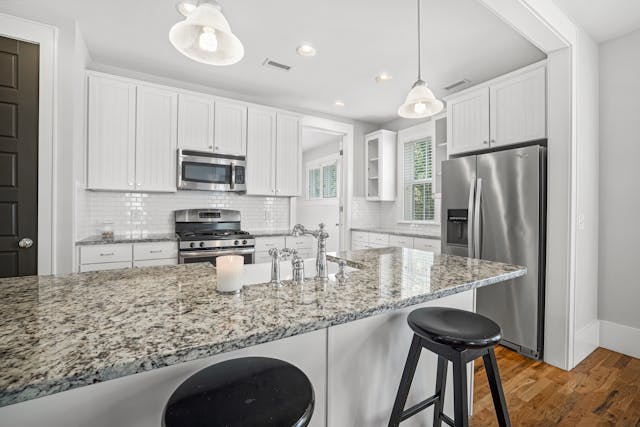 a white kitchen with stainless steel appliances and granite counters