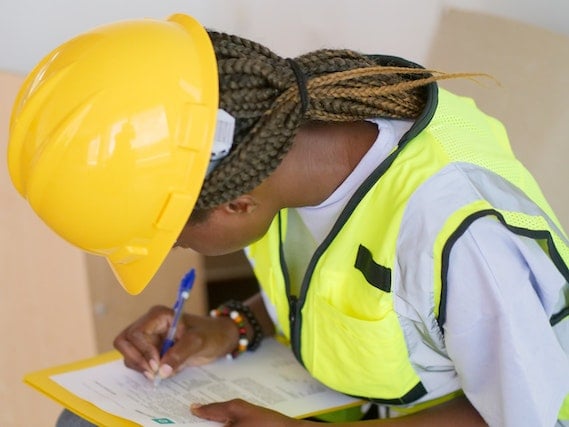 person in yellow hard hat and reflective vest filling out home inspection form