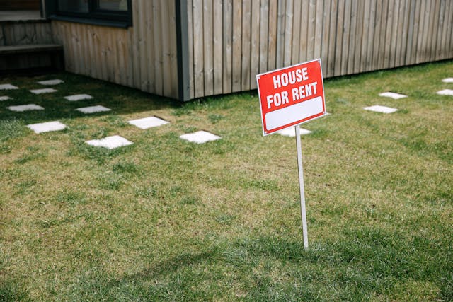 a red for rent sign in a front yard