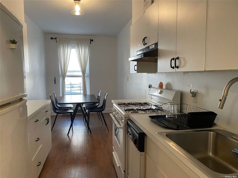 Beautiful kitchen with cabinetry, gas stove, sink, and four-chair dining table