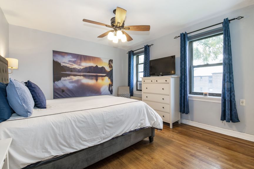 Second bedroom with two windows, a bed, and dresser with a tv