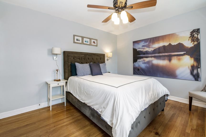 Second bedroom with a bed, bedside table, and a ceiling fan