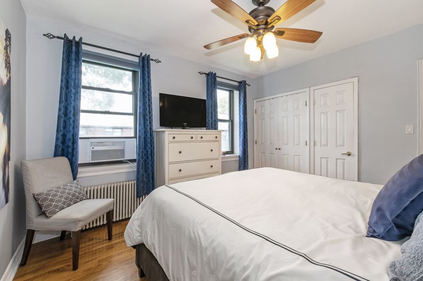 Second bedroom with two windows, a bed, and dresser with a tv