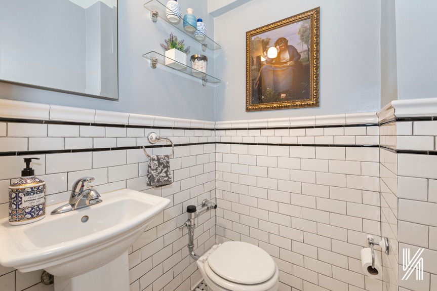 Half bathroom with a decent white tiles, a painting and a beautiful mirror