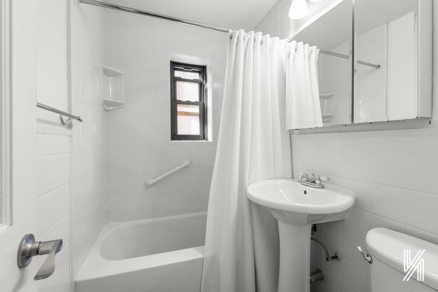 Bathroom with white tiles, a sink, and a beautiful mirror