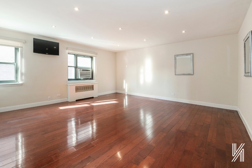 An empty living room with a TV and a window