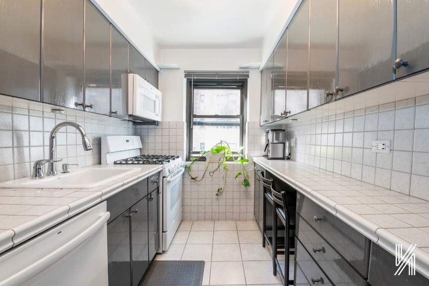Galley kitchen with countertops on both sides, glossy cabinetry, and a dishwasher