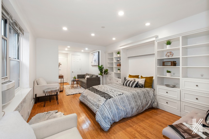 Room with bed and large window and shelves connected to living room