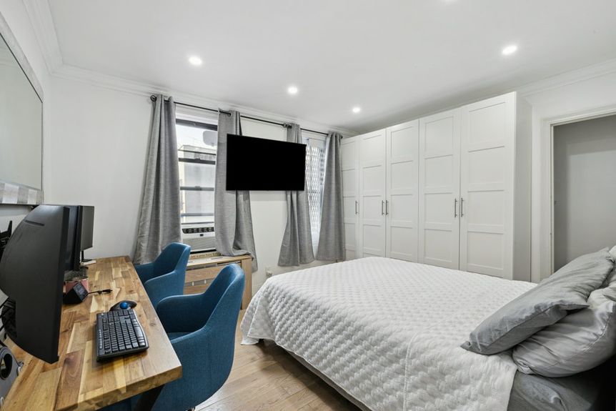 Bedroom with beautiful white closets and two computers, two chairs, and a computer desk.