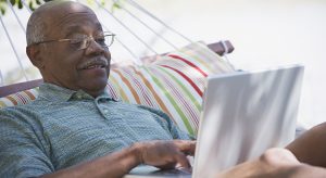 Senior African man using laptop in hammock