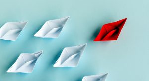 Leadership Concept – Red Paper Boat Followed by White Paper Boat on Blue Background