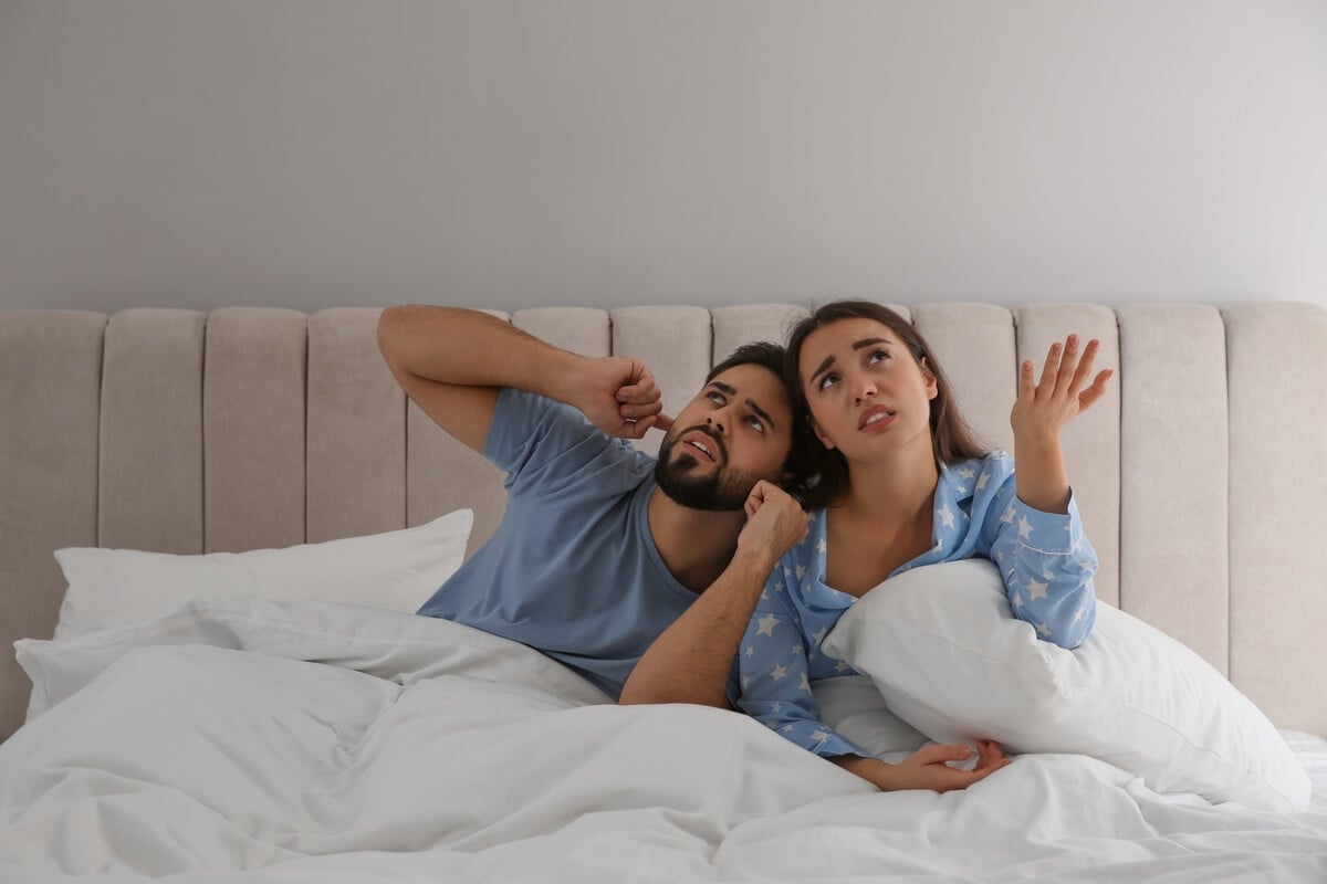 A couple in bed being upset because of noisy neighbors