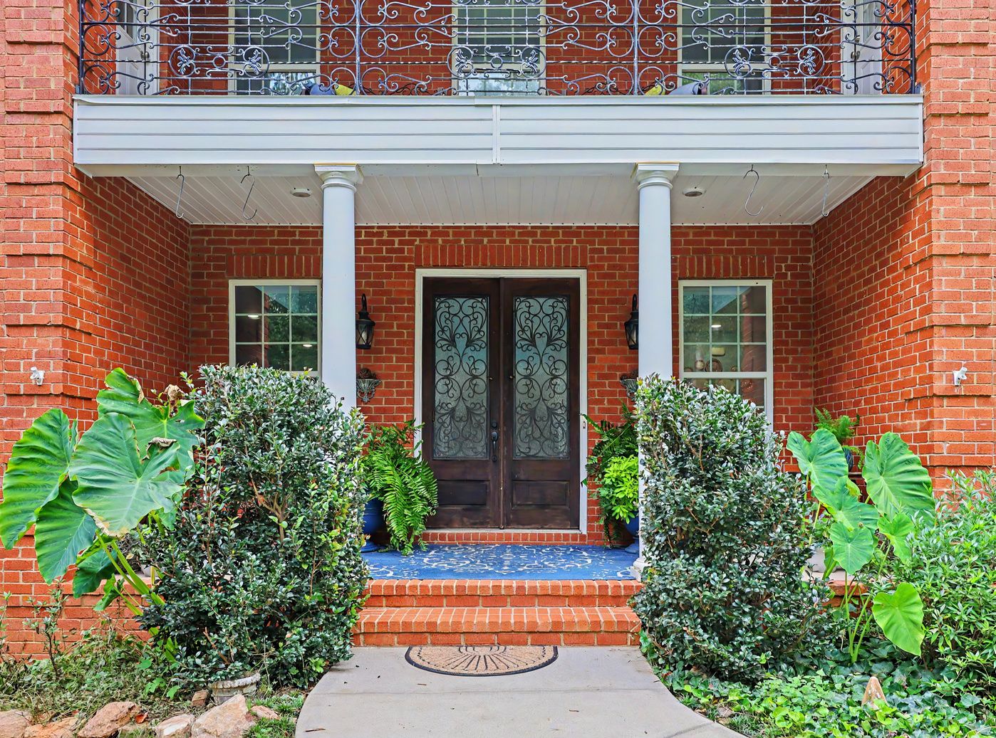 Columned front porch with wrought-iron double doors