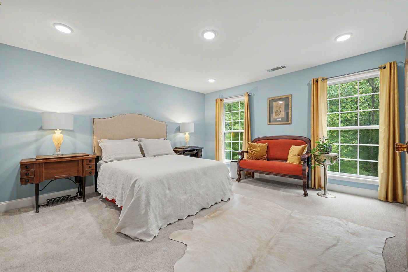 Guest bedroom with upholstered headboard and antique settee
