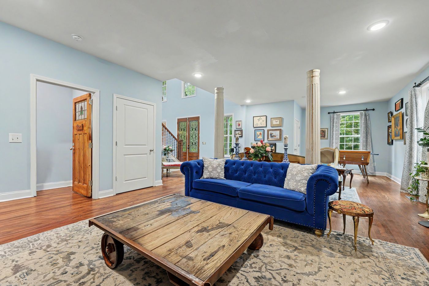 Living room with a sapphire tufted sofa, industrial cart coffee table and framed art