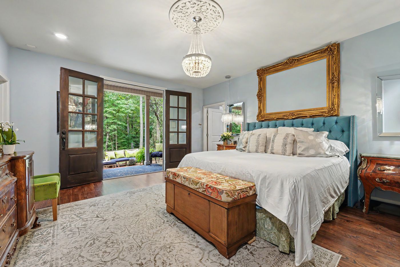 Primary suite with a gilded mirror, antique chest and French doors to the porch