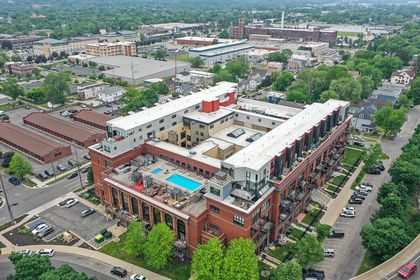 Drone photo of Union Square Condos showing the U‑shaped red‑brick complex with a rooftop pool deck and surrounding Grand Rapids neighborhood.