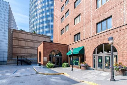 Wider view showing twin brick vestibules, green awnings, planters, and the side of a high‑rise tower in the background.
