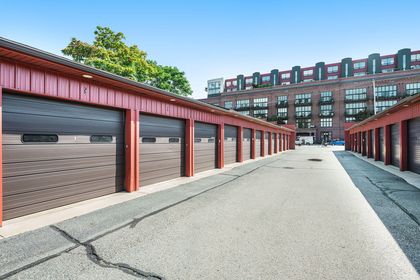 Row of red metal garages with dark brown doors, Union Square’s brick building visible beyond.