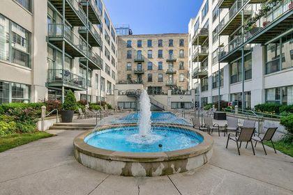Circular fountain spraying water in the foreground with the rectangular pool and condo balconies extending behind it inside the courtyard.