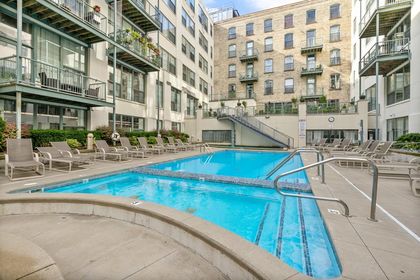Courtyard pool at Boardwalk Condos with a shallow lounging shelf in the foreground, rows of tan chaise lounges along both sides, and historic brick facade rising behind.