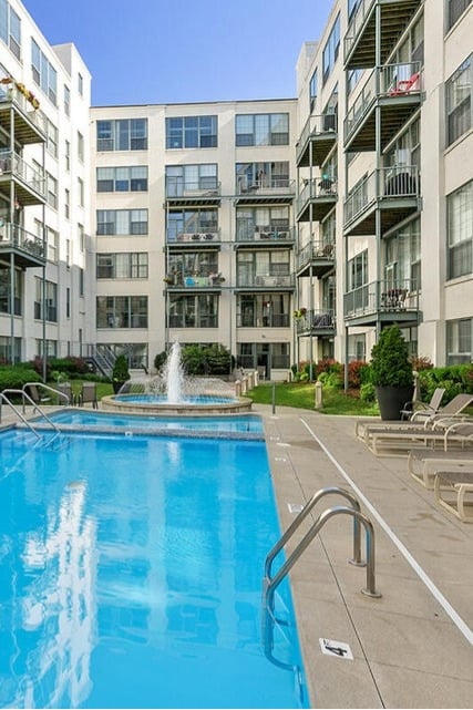 Rectangular outdoor pool with a central fountain, lounge chairs, and balconies of surrounding condo units overlooking the courtyard at Boardwalk Condos.