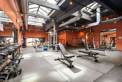 Spacious condo gym with skylights, exposed ductwork, brick walls, free weights, and cardio machines.