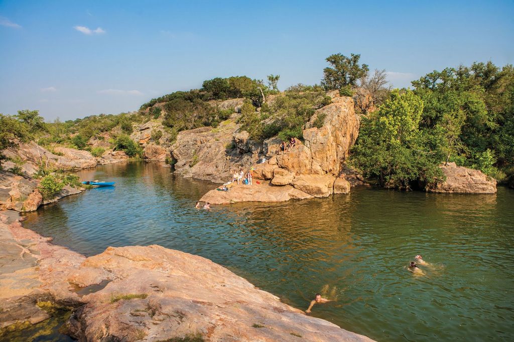 Devil’s Waterhole at Inks Lake State Park with clear water surrounded by rocky cliffs and trees.