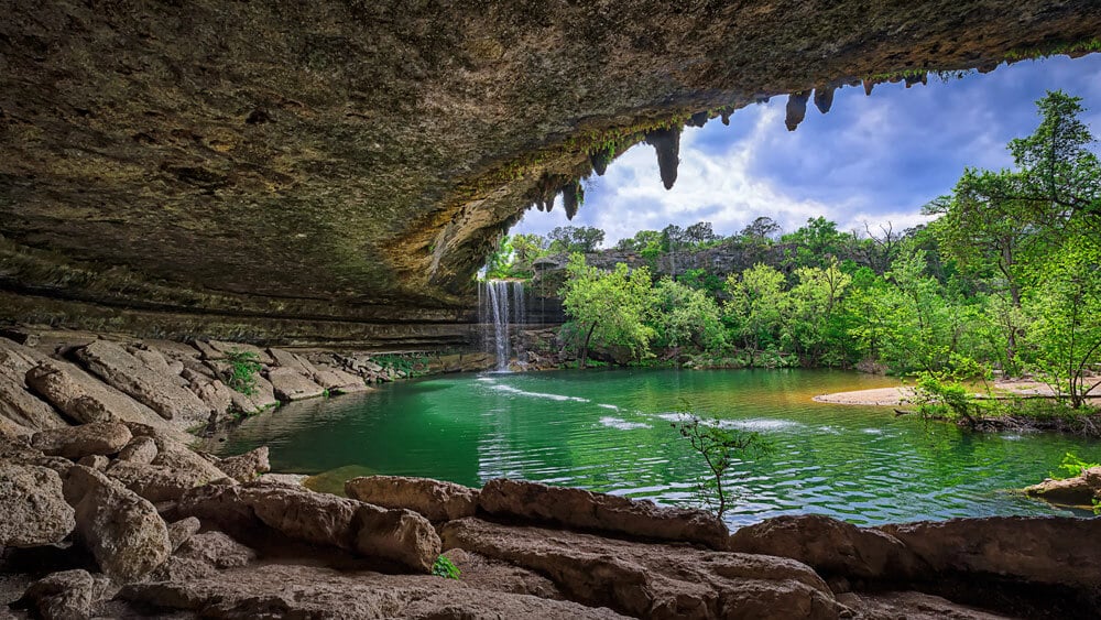 Hamilton Pool Preserve near Lake Travis showing natural limestone grotto, waterfall, and emerald green swimming hole in the Texas Hill Country.