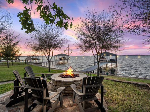 Lake LBJ waterfront home with fire pit seating area overlooking lake and boat docks at sunset in Texas Hill Country