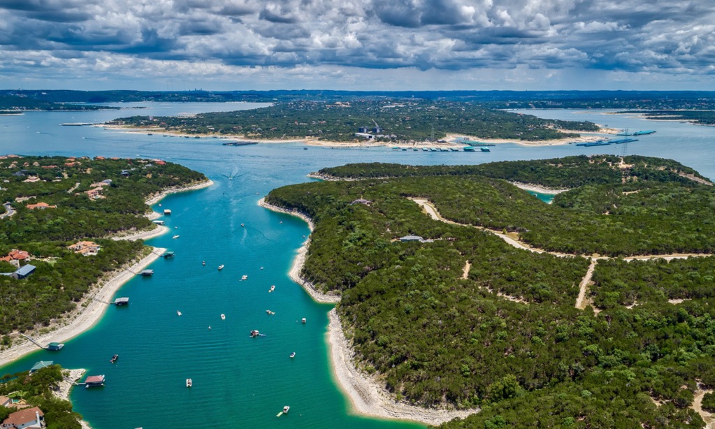 Aerial view of waterfront homes and shoreline along a Central Texas Highland Lake with docks, open water, and Hill Country scenery.